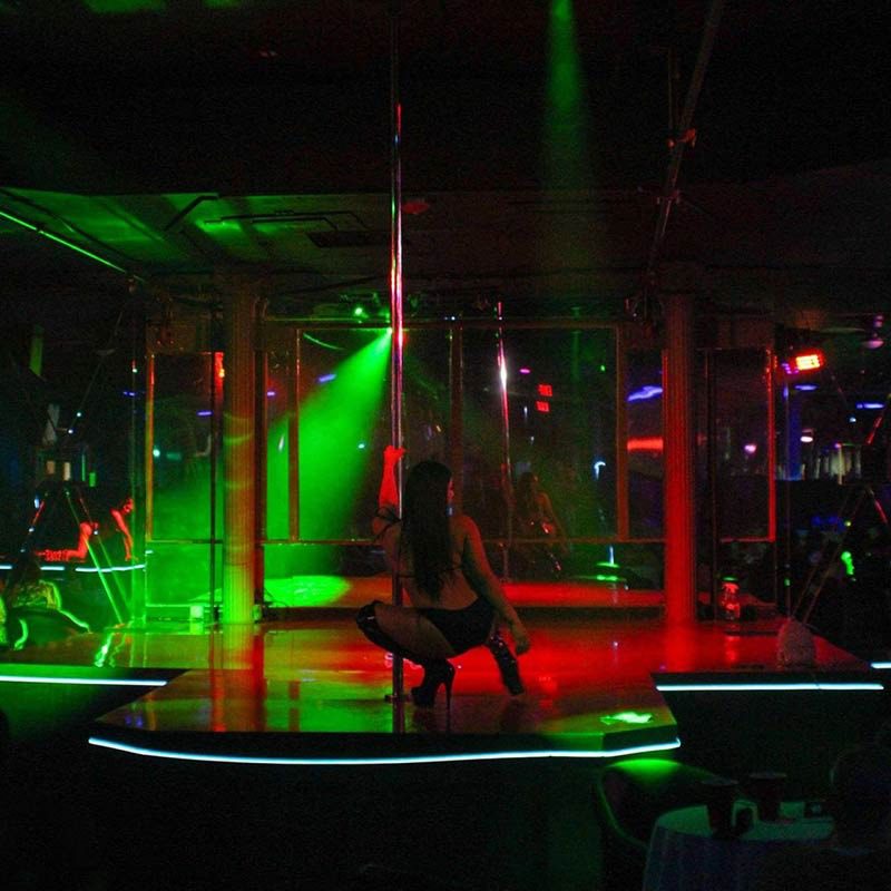 A dancer on the green lit stage with the room behind her